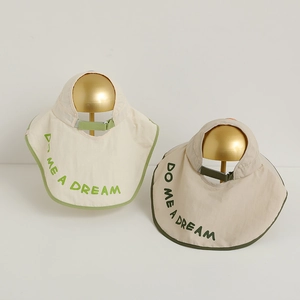 Detail of kids sun hats in beige and khaki with green piping and letter embroidery
