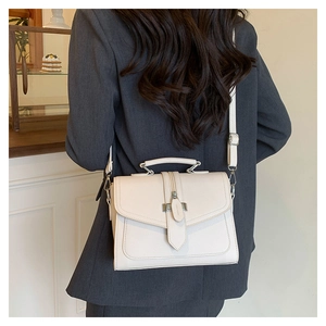 Detailed view of a white textured PU leather shoulder bag worn over a grey blazer