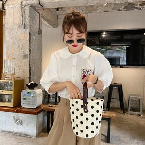 French vintage polka dot canvas bucket bag with brown leather handles in a cafe setting
