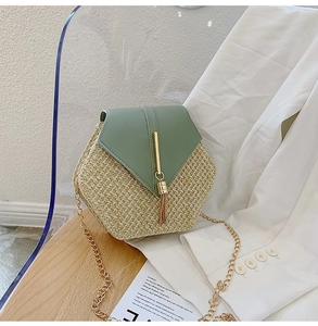 Close-up of woven straw handbag with sage green leather flap and gold tassel detail