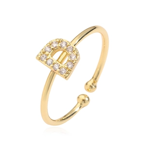 Macro shot of gold-plated open ring with letter D shape and sparkling cubic zirconia