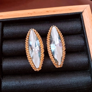 Macro detail of marquise-cut crystal earrings with gold beaded edges on black velvet