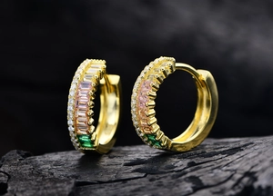Macro detail of gold hoop earrings set with colorful rectangular zircons and white crystals