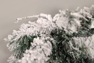 Detailed close-up of realistic snow-flocked PVC pine needles on a hanging Christmas tree