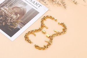 Close-up of golden double-layer chain bracelet with padlock and key charms