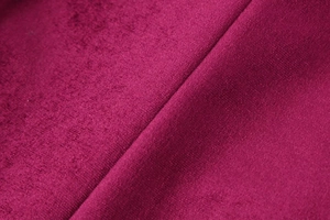 Close-up of velvet fabric in magenta with detailed stitching on the suit pants