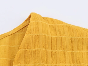 Dettaglio ravvicinato del tessuto seersucker giallo testurizzato e del design a pieghe
