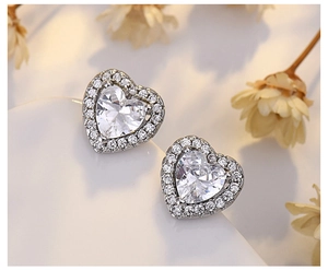 Macro shot of silver heart stud earrings with sparkling cubic zirconia on a white surface