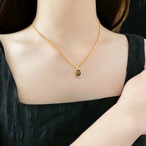 Gros plan d'un collier doré avec pendentif œil de tigre sur le cou d'un mannequin