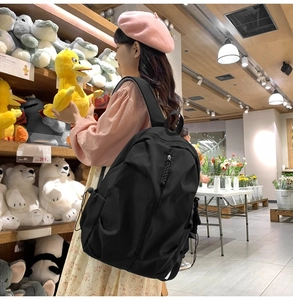 Side view of black nylon backpack featuring adjustable drawstring side pocket for water bottle