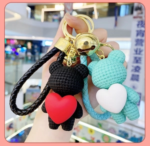 Detail of creative resin heart bear keychains in black and mint green with golden bells