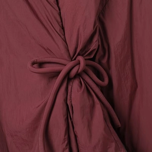 Vista macro detallada de la chaqueta de kimono granate con un diseño de nudo acolchado