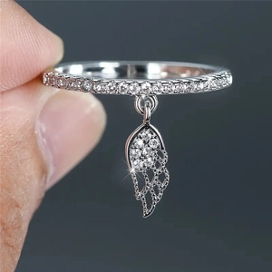 Macro shot of silver feather charm ring with zircon pavé detail and delicate wing pendant