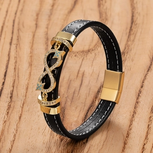 Detail of black leather bracelet with golden infinity charm and turquoise accents on wood