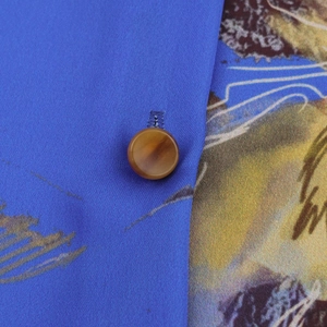 Vista macro dettagliata del tessuto satinato blu con stampa floreale e un bottone marrone