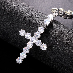 Sparkling silver cross pendant necklace with clear zircons on black textured background