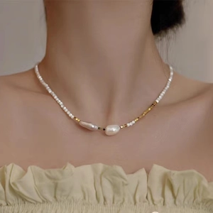 Close-up of Baroque pearl necklace with gold beads and white pearls on a model neck