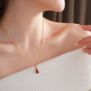 Close-up of gold-plated necklace featuring a red agate gourd pendant on a model