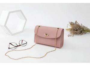 Détail du sac à bandoulière en cuir rose montrant le fermoir doré et le côté en accordéon