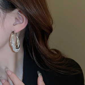 Close-up of elegant silver double hoop earrings with sparkling diamond inner ring texture