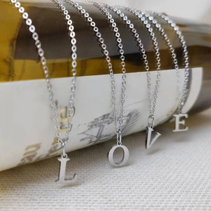 Silver stainless steel letter pendants forming LOVE hanging from a wine bottle neck