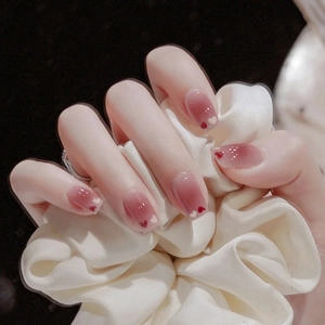 Close-up of pink gradient press-on nails with small red and white heart patterns