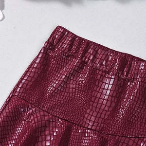 Close-up of burgundy faux leather texture with embossed animal pattern and elastic waist