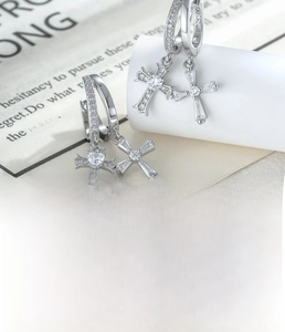 Detailed macro view of silver lace cross hoop earrings with white zircon inlays