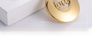 Macro shot of gold plated titanium steel round charm with hollow love lettering detail