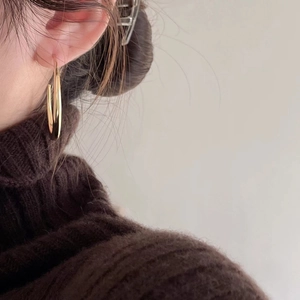 Classic gold hoop earrings with polished finish worn by a model in a knit sweater