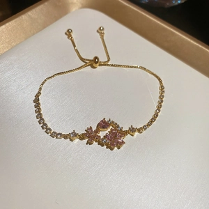 Macro shot of gold-plated bracelet with pink zircon flower and adjustable pull chain