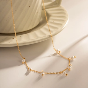 Detail of 18K gold stainless steel chain necklace with small white freshwater pearls