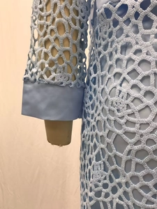 Détail d'une robe en dentelle bleu clair montrant les motifs ajourés sur la manche