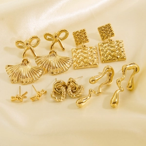Flat lay of multiple 14K gold-plated stainless steel earrings on a satin background