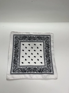 Flat lay of a white square bandana with black paisley patterns and hemmed edges