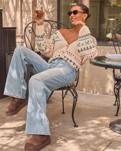 Detailopname van een wide-leg jeans met hoge taille en een gebreid vest met patroon