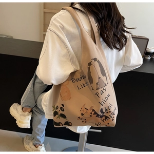 Back view of beige tote bag with cute animal illustrations on a model in a casual outfit