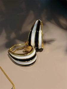 Macro shot of 18K gold plated C-shaped earrings with black and white striped enamel details
