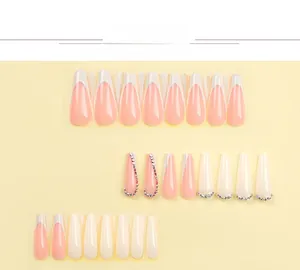 Macro view of French tip press-on nails with luxury rhinestones and chain details
