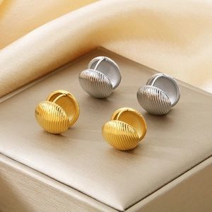 Detailed close-up of shell-textured gold and silver hoop earrings on silk fabric