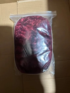Deep red long wavy wig with bangs neatly packaged in a transparent protective bag