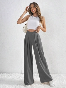 Detail showing high-waisted dark grey wide-leg trousers with pleated crepe fabric texture