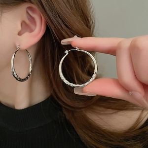 Detailed view of silver hoop earrings with a textured geometric diamond-cut pattern