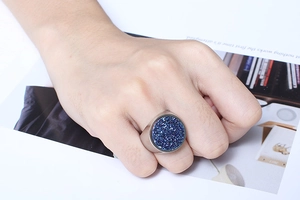 Close-up of a large silver ring with a blue druzy stone on a fashion magazine background