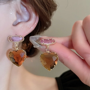 Close-up of elegant heart-shaped crystal earrings with pink and brown gemstones on gold plating