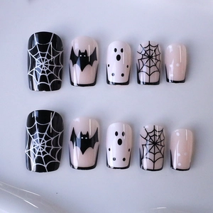 Halloween press-on nails featuring black bats, spider webs, and ghost designs on white