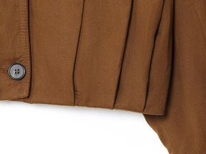 Close-up of brown twill fabric texture with a dark grey button and pleated detail