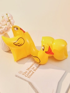Inflatable yellow duck arm floaties for children swimming aid on wooden surface