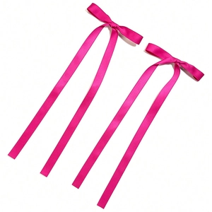 Detailed close-up of two pink satin ribbon bow hair clips with long tails on white background