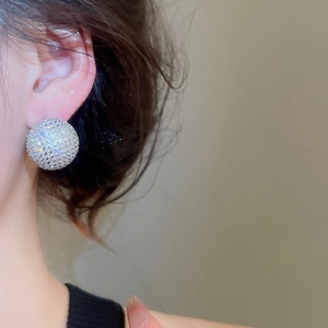 Close-up of sparkling zircon stud earrings with dense pavé setting on a model